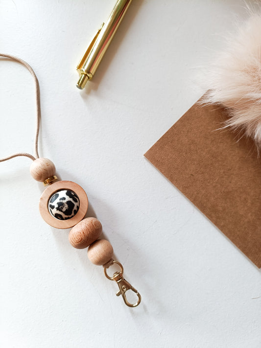 Leopard print lanyard with wooden detail on white desk with pen