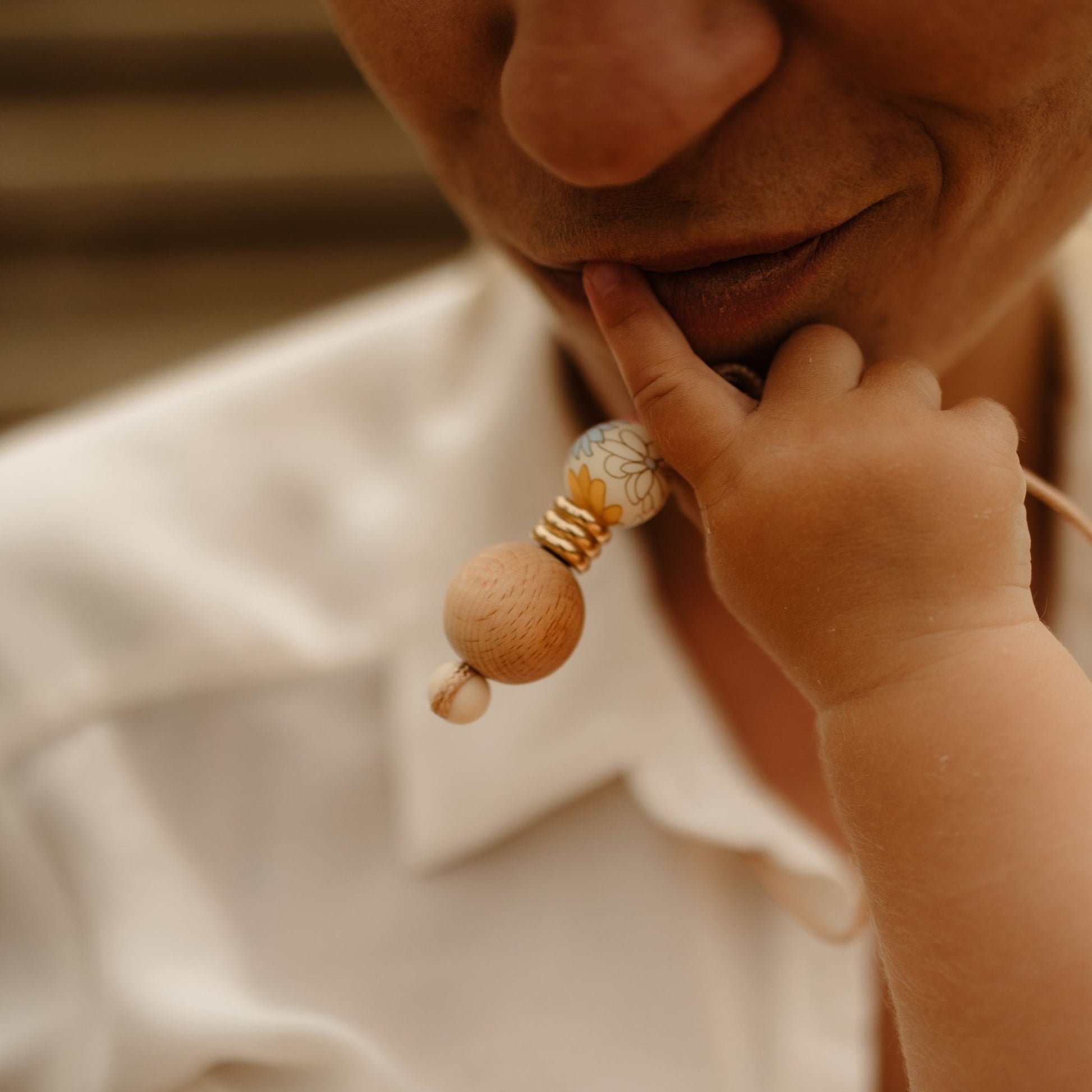 Boho Bloom teething Pendant held up by baby while feeding.