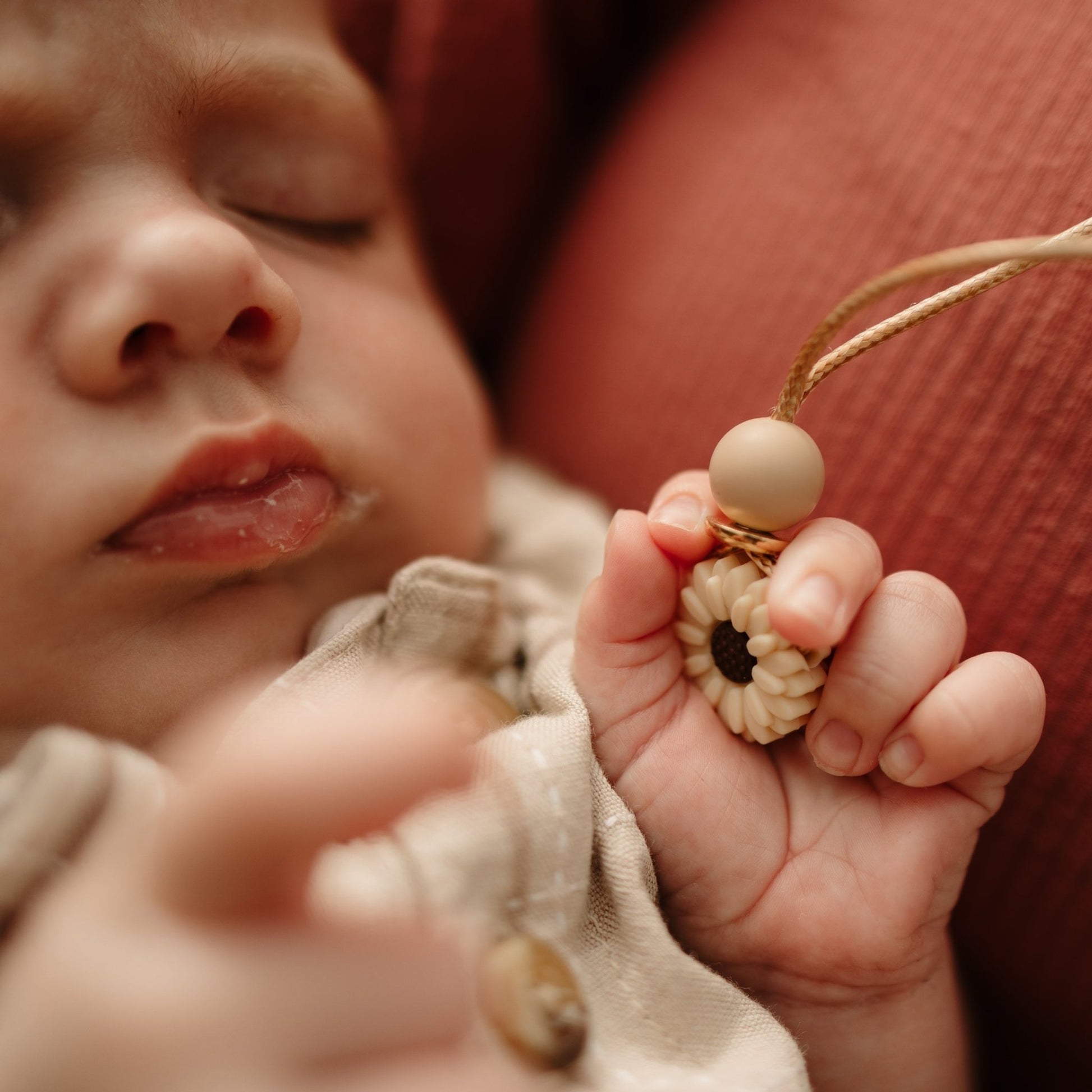 Dainty Daisy cream flower shaped Pendant being held by baby.
