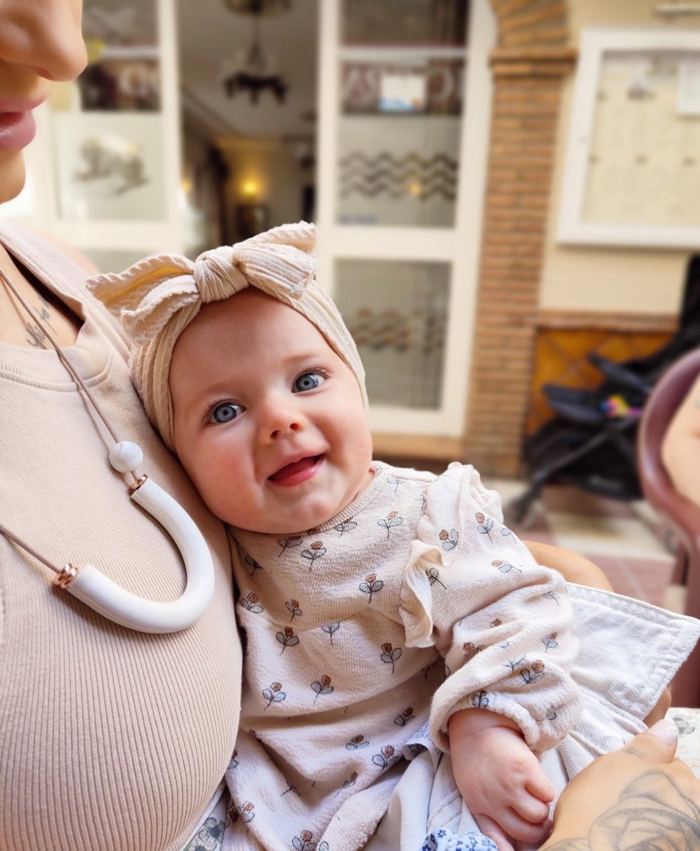 mum wearing Toffee Dream Necklace with baby smiling on lap.