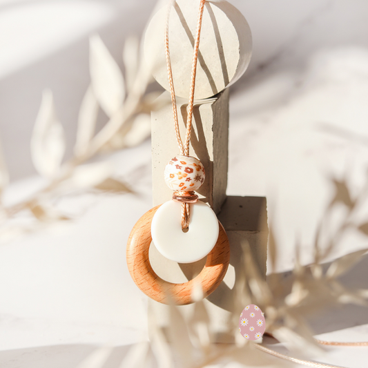 breastfeeding and teething necklace hung on white background with floral details.