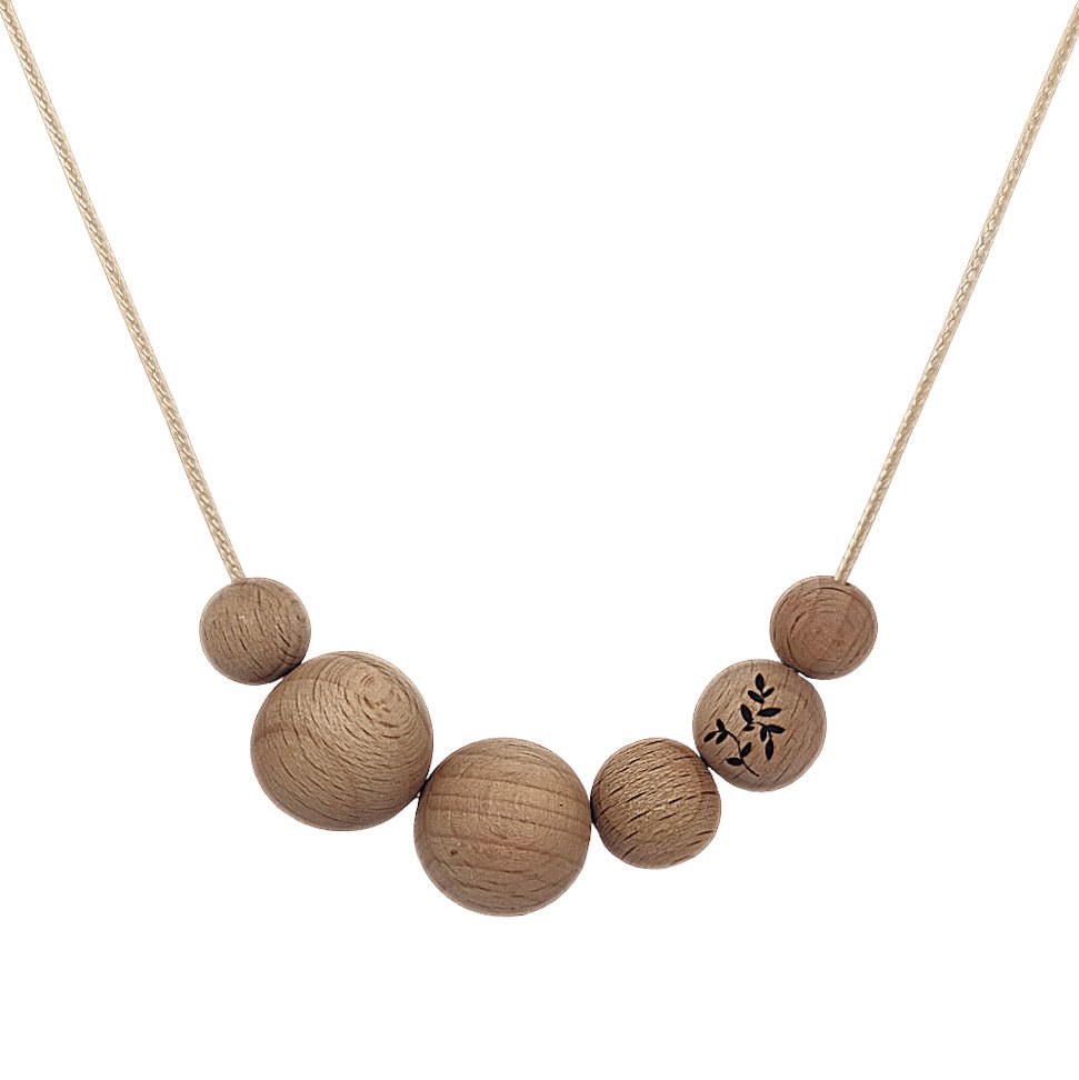 Blossy Naturals Beechwood Necklace hung on white background with engraving detail.