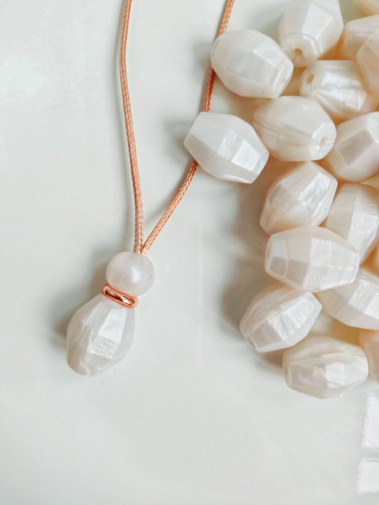 Pearl Drop Pendant with rose gold detail on white background taken by blossy.